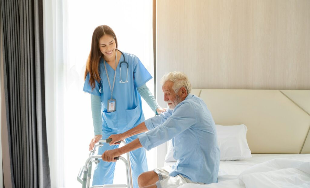 Care worker helping elderly man get out of bed.